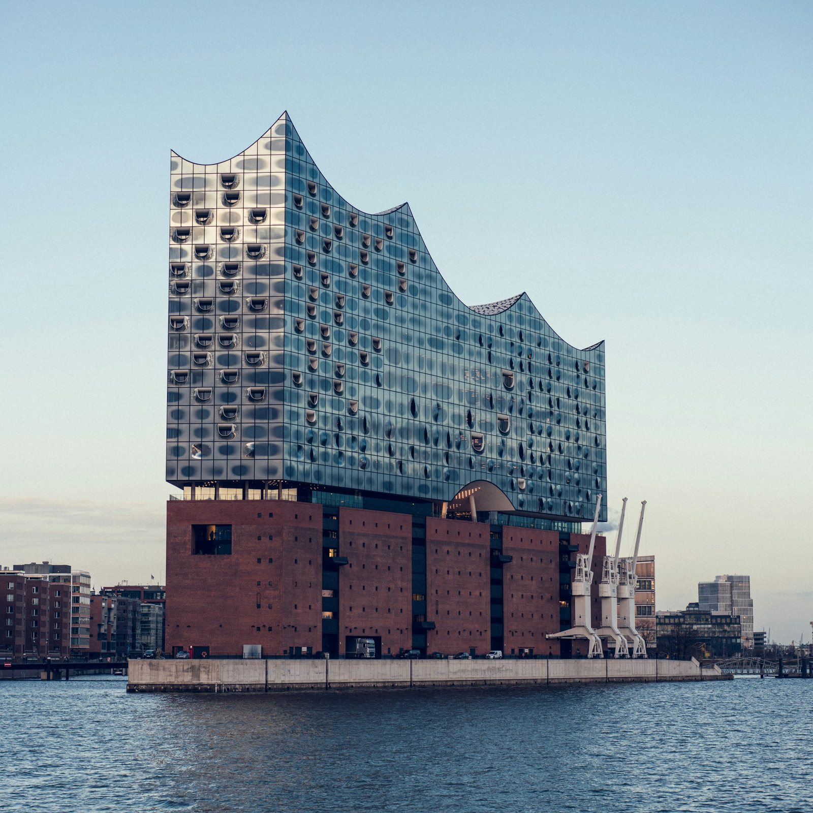Die Elbphilharmonie in Hamburg am Wasser vor klarem Himmel