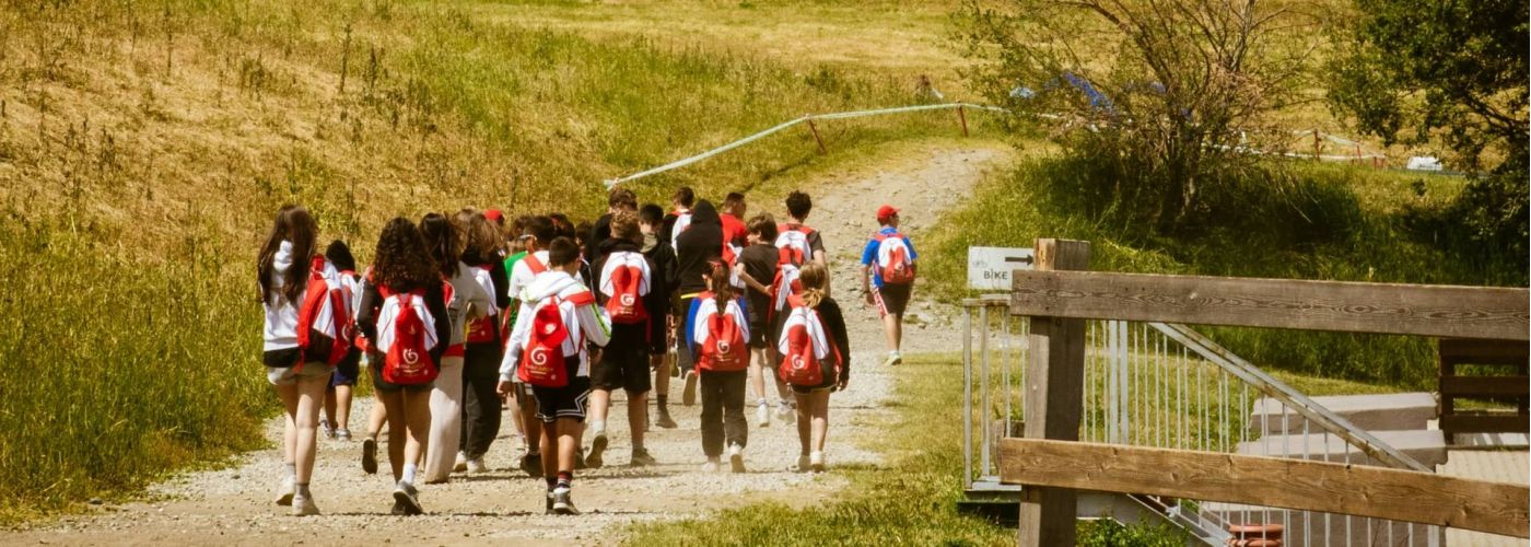 Schulklasse wandert mit Rucksäcken in einer Gruppe auf einem Weg durch eine Berglandschaft