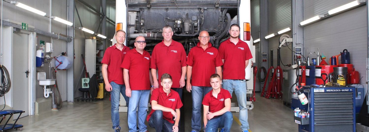 Das Werkstatt-Team von Dornburg Reisen vor einem Reisebus mit geöffnetem Motorraum