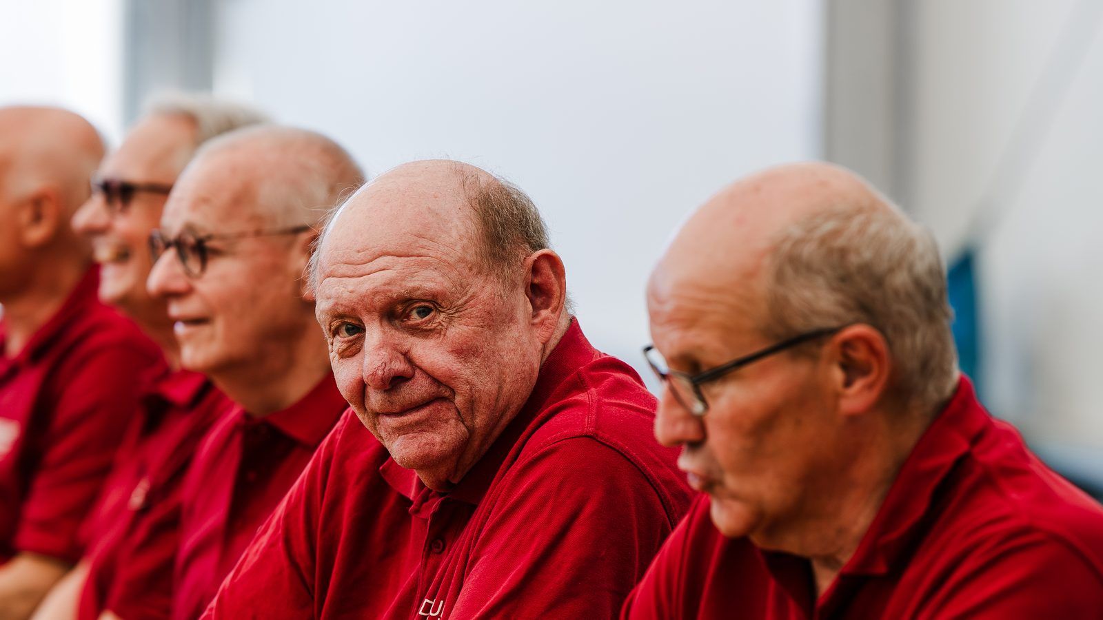 Drei ältere Fahrer von Dornburg Reisen in roten Poloshirts beim Betriebsfest, einer blickt lächelnd in die Kamera