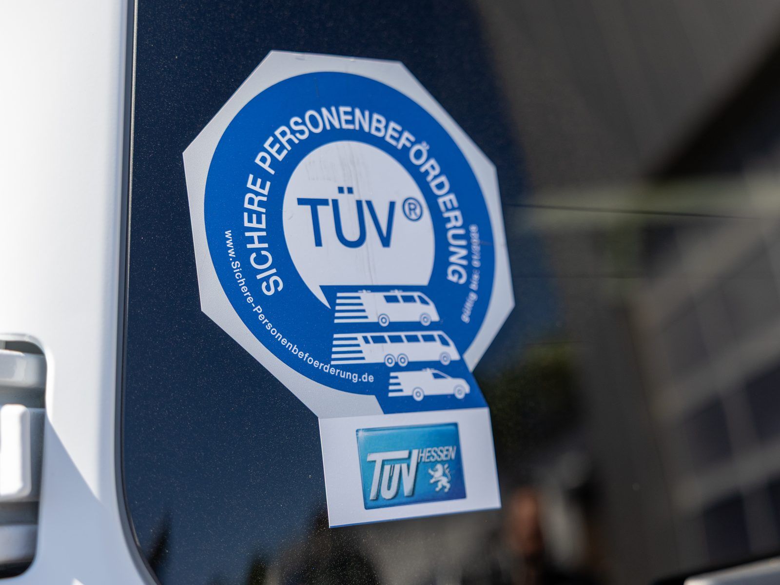 Plakette &bdquo;Sichere Personenbef&ouml;rderung&ldquo; mit T&Uuml;V-Hessen-Siegel an der Scheibe eines Busses von Dornburg Reisen
