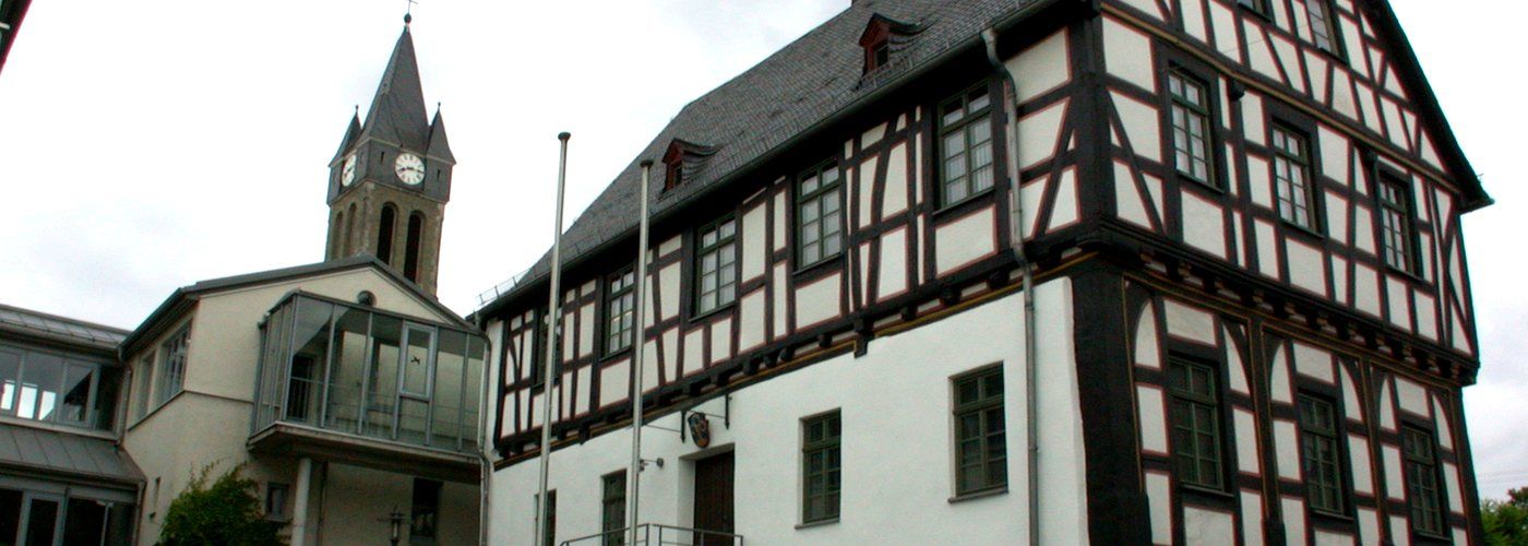 Rathaus der Gemeinde Elz, Fachwerkgebäude mit Turm der Pfarrkirche im Hintergrund